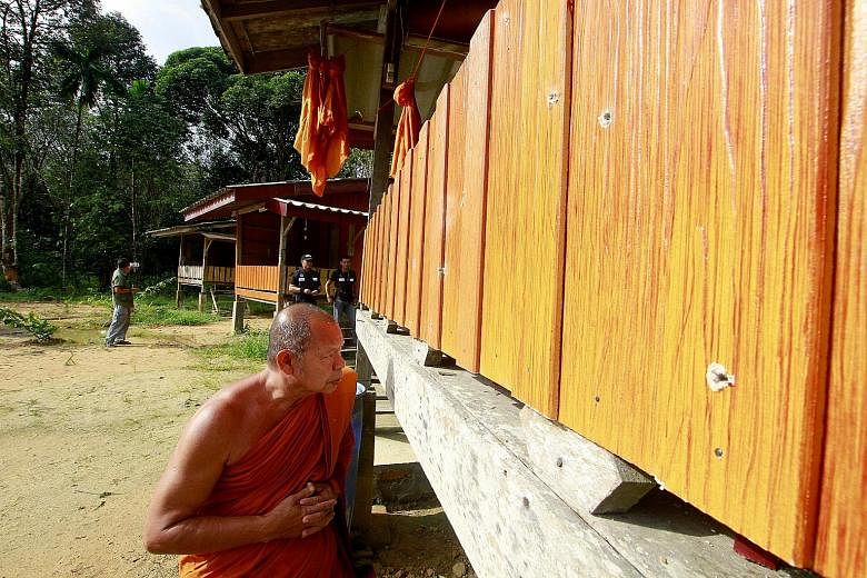 A Buddhist monk looking at bullet holes in the wall of a monk's shelter at the Rattanupap temple in Narathiwat province yesterday.