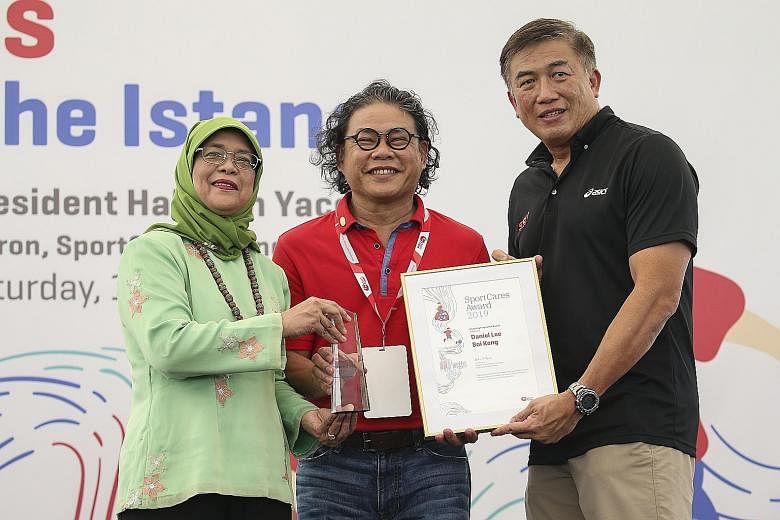 Wheelchair rugby coach Daniel Lee (centre) receives his Coaching Inspiration Award from President Halimah Yacob and Sport Singapore chief executive Lim Teck Yin at the SportCares Awards yesterday.