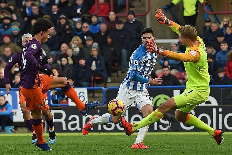Manchester City's German midfielder Leroy Sane shoots past Huddersfield goalkeeper Jonas Lossl to score their third goal in the 3-0 victory yesterday.