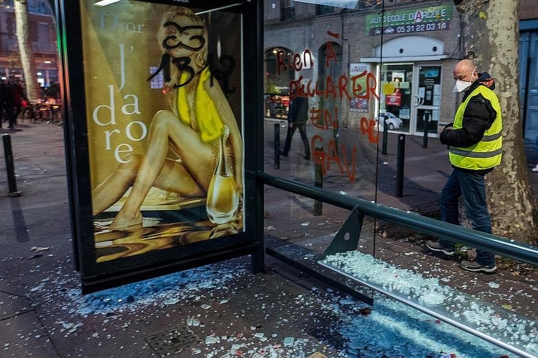 A "yellow vest" protester looking at a damaged bus-stop in the aftermath of a demonstration in the southern city of Toulouse on Saturday.