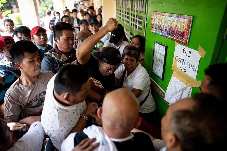 A crowd of voters attacking a person (hidden) accused of casting multiple votes yesterday in Cotabato, Mindanao. Officials said the referendum was uneventful overall despite reports of "flying voters" and harassment of poll officials.