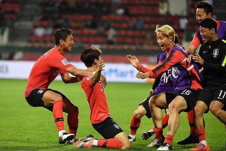 South Korean players celebrate substitute Kim Jin-su's (kneeling) extra-time goal against Bahrain. The left-back's header sent the Koreans through to the quarter-finals with a 2-1 win.