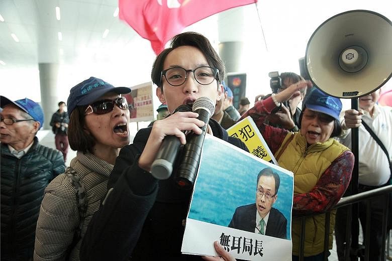 A pro-democracy activist holding a sign showing Secretary for Constitutional and Mainland Affairs Patrick Nip in Hong Kong yesterday.