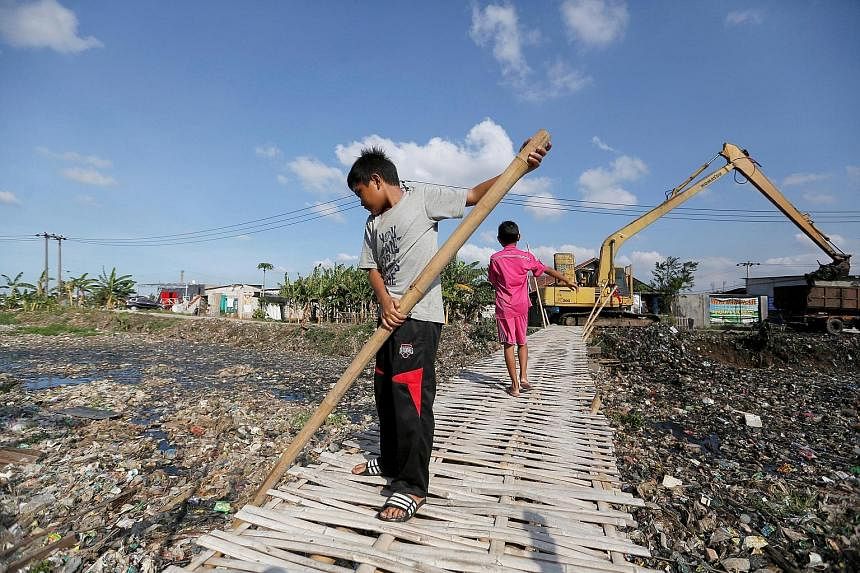 A boy using a bamboo stick to clean a river covered by rubbish in Bekasi, West Java, earlier this month. The river is among several in Indonesia thickly carpeted with trash formed mostly of plastic waste. The country is battling a lack of environment