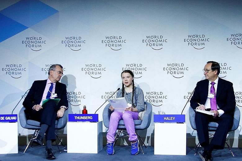 Young climate crusader Greta Thunberg with French central bank governor Francois Villeroy de Galhau (left) and consultancy firm Willis Towers Watson's CEO John Haley at a WEF panel discussion in Davos yesterday.