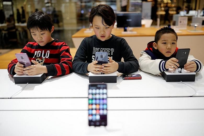 Children trying out Samsung Electronics' Galaxy S9 at its store in Seoul earlier this month. Samsung is expected to report downbeat fourth-quarter results on Jan 31.