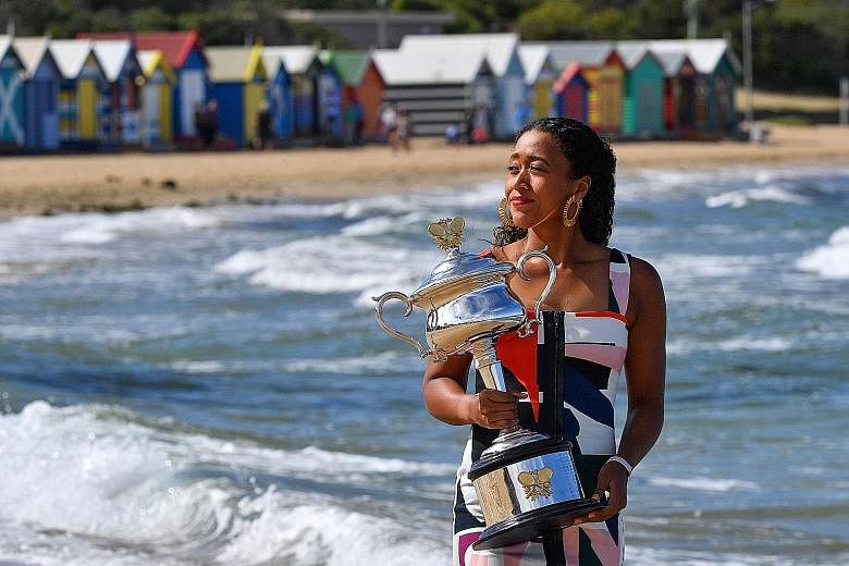 Australian Open winner Naomi Osaka holding the championship trophy at Brighton Beach in Melbourne yesterday. The 21-year-old Japanese will rise to world No. 1 today.