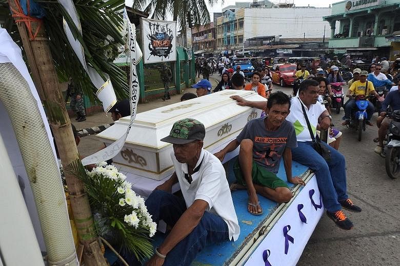 Mourners sitting on a hearse during the funeral procession for a victim of the Jan 27 church bombing in Jolo, in Sulu province.