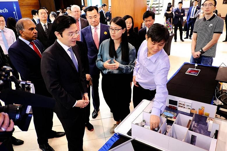 Mr Lawrence Wong (front row, left), Second Minister for Finance and National Development Minister, viewing an NTU research project that leverages on cutting-edge technology such as the Internet of Things, at the opening ceremony yesterday of the rese