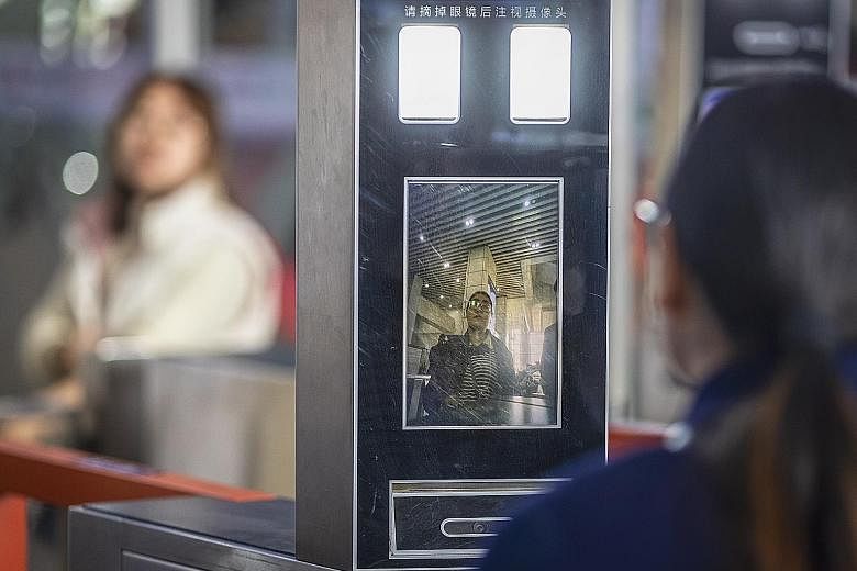 Above: Policemen patrolling with a security robot at a railway station in Shenzhen last week. Left: A woman having her face scanned by a ticket machine at a railway station in Guangzhou on Sunday.