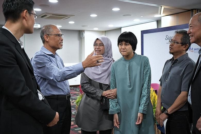 Minister-in-charge of Muslim Affairs Masagos Zulkifli, with Muis chief executive Esa Masood (left) and Special Needs Trust Company chairman Moses Lee (right), speaking with Muis Special Needs Trust Scheme beneficiary Nazurah Noorabidin and her parent