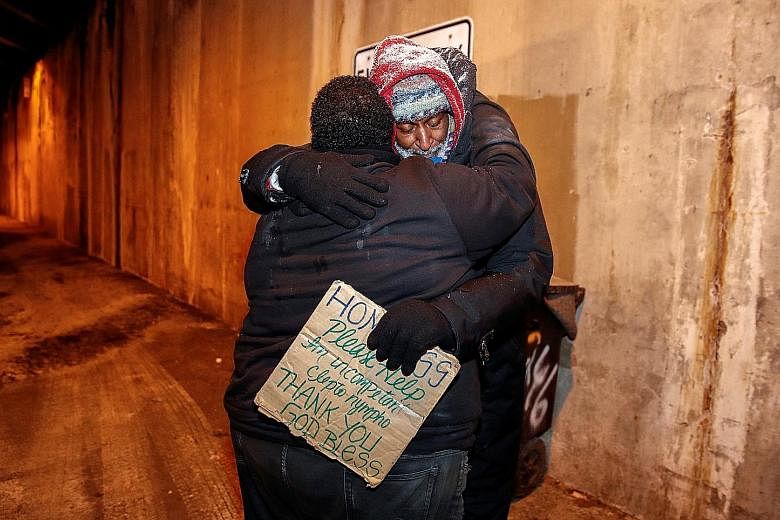An official of the Salvation Army hugging a homeless person during a cold wellness check-up in Chicago on Thursday. US Coast Guard staff using a boat as an ice breaker on the Hudson River, between the towns of Kingston and Poughkeepsie, in New York, 