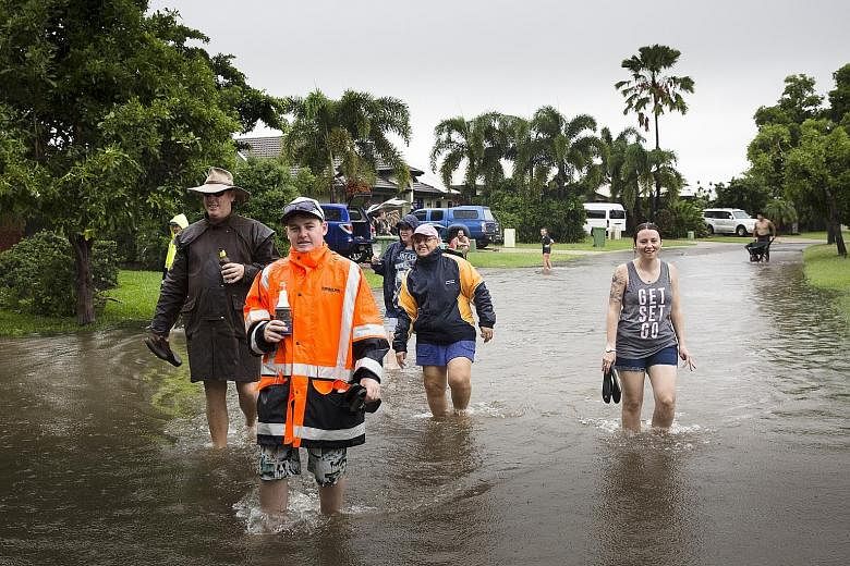 Floodwaters at Aplins Weir in Townsville on Friday. The local authorities issued a number of flood warnings yesterday morning. People wading in floodwaters in Townsville on Friday. Residents were told to leave their homes as Queensland's flood disast