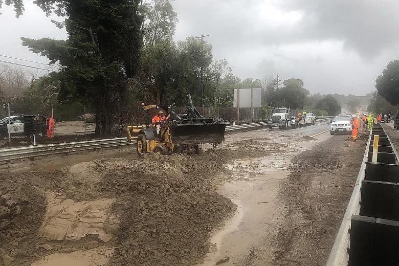 Heavy equipment being used to clear US Highway 101 of mud and water from Romero and San Ysidro creeks in Montecito, California, on Saturday. Heavy rains during the night caused road flooding and numerous trees to fall.