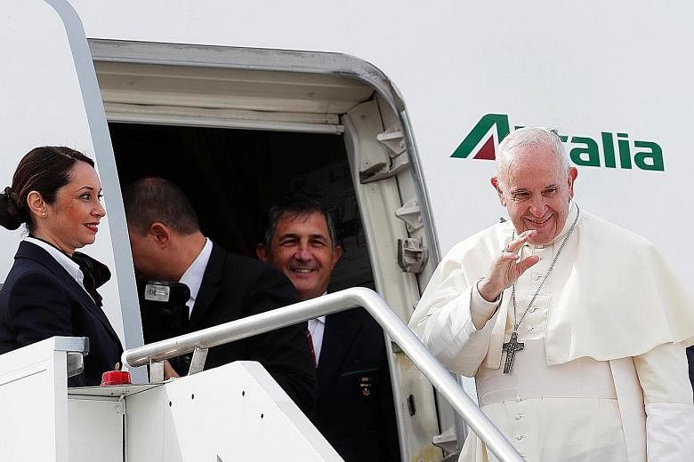 Pope Francis waves as he boards a plane at Leonardo da Vinci-Fiumicino Airport in Rome before departing for his visit to the United Arab Emirates.