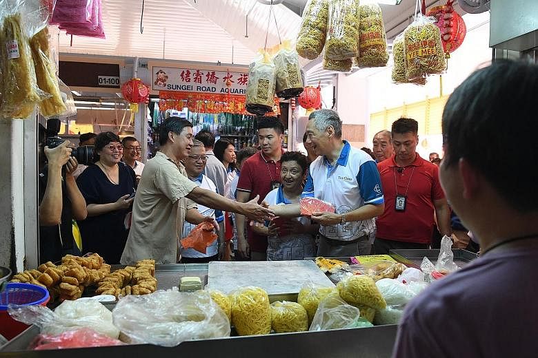 Prime Minister Lee Hsien Loong greeting a stall owner during a visit yesterday to Teck Ghee market in Ang Mo Kio, where he met residents and stall owners to exchange New Year greetings and give out red packets.
