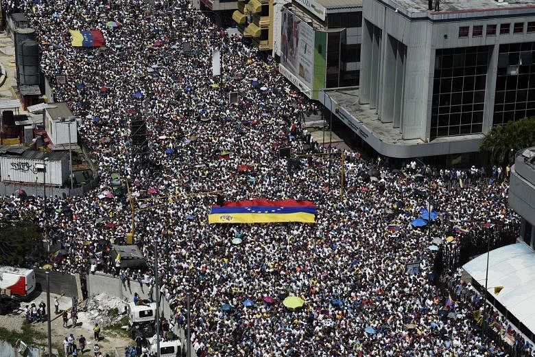 Protesters hoisting a Venezuelan flag as they poured onto the streets in Caracas on Saturday to back self-proclaimed president Juan Guaido's call for early elections.