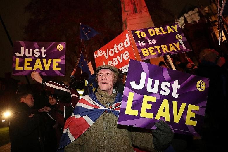 Pro-Brexit demonstrators outside Britain's Parliament in London last Tuesday. On March 29, unless something is done, Britain will fall out of the European Union without a deal. That will affect every aspect of the economy, says the writer.