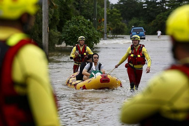 Queensland Fire and Emergency Services crew members using an inflatable boat to pull residents through floodwaters in Hermit Park, Townsville.