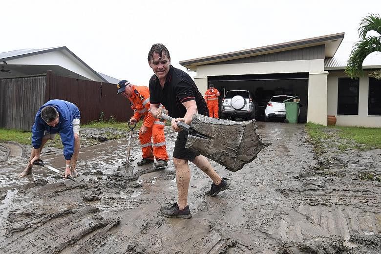 Residents clearing mud off their driveway in Hermit Park, Townsville, in Queensland after days of torrential rain caused massive floods.