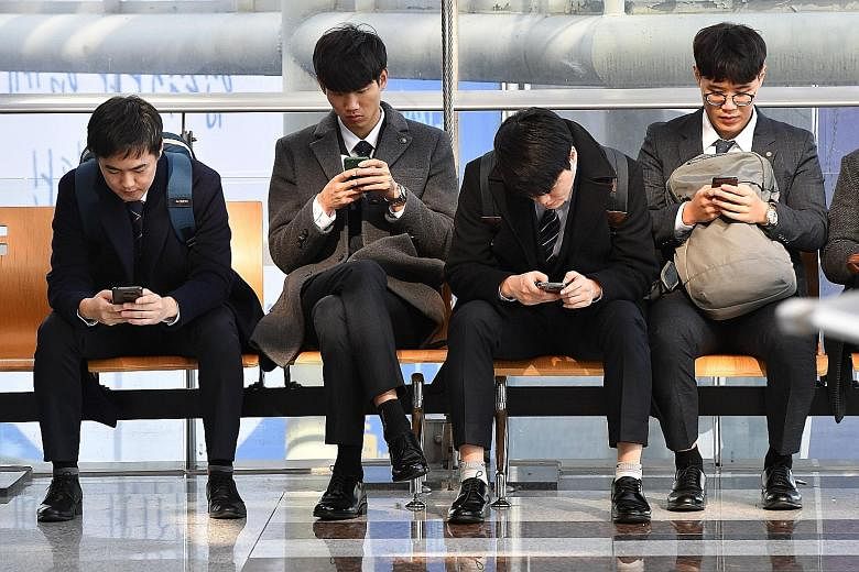 South Koreans checking their smartphones. A Pew Research Centre report has found strong majorities of adults using smartphones in the world's wealthier countries, led by a 95 per cent adoption rate in South Korea.