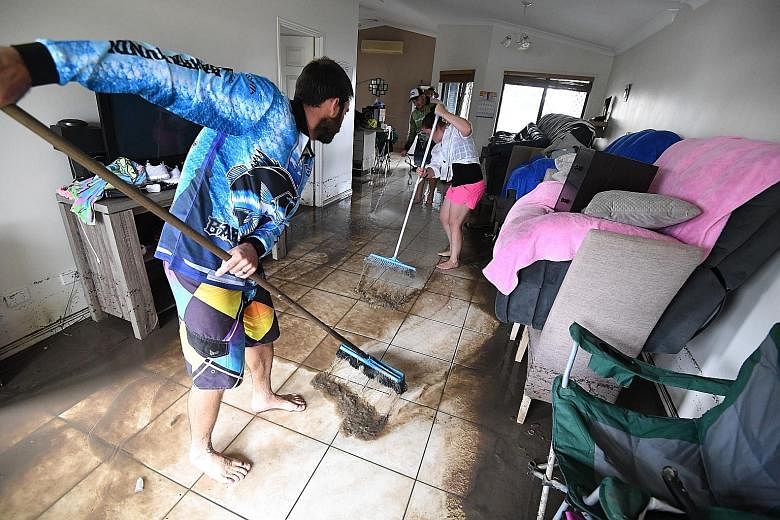 Above: Residents clearing mud from their house in Townsville. Prime Minister Scott Morrison and Queensland Premier Annastacia Palaszczuk said officials are working to ensure affected locals would get access to recovery payments and support.