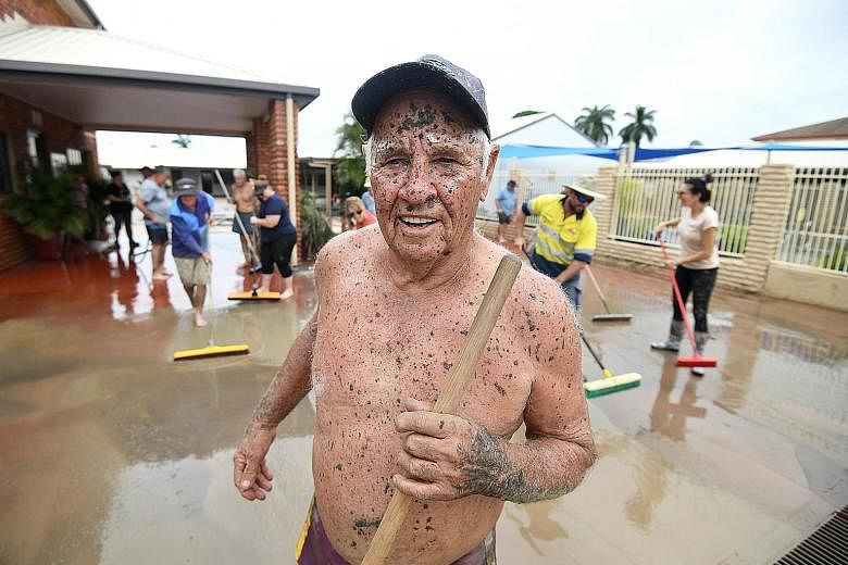 Left: Townsville resident Dave Mitchell helping to clean his brother's motel on Tuesday.