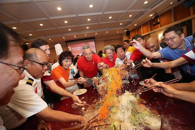 Prime Minister Lee Hsien Loong, Mrs Lee and NTUC president Mary Liew (in orange) having a lohei session with workers, union leaders and management staff at ground-handling and catering firm Sats at Changi Airport on Tuesday, the first day of the Chin