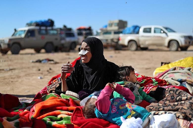 A woman and two children who had fled the fighting between the Syrian Democratic Forces (SDF) and ISIS militants in the Syrian village of Baghuz waiting to be screened and registered by the SDF on Sunday.
