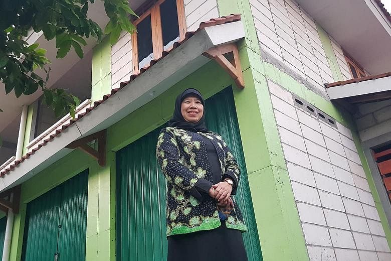 Shopkeeper Ngadiyem in front of her dome house - one of 80 such houses in New Ngelepen village in Sleman. They are made of concrete and reinforced with steel, which can help them withstand storms and quakes. They also look similar to the homes in the