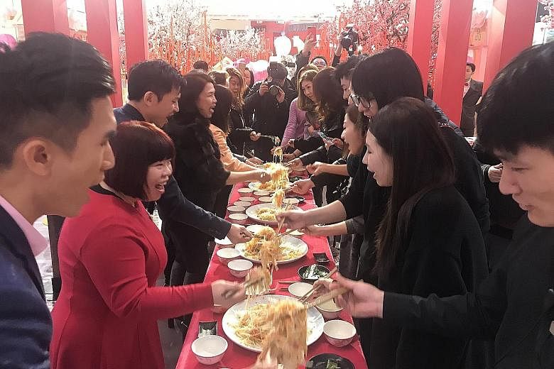 Shoppers and staff of Crystal Galleria, a mall in downtown Shanghai, joining the Singapore Chinese Cultural Centre (SCCC) delegation in tossing yusheng - or lo hei - yesterday, the seventh day of the Chinese New Year. The custom of eating raw fish is