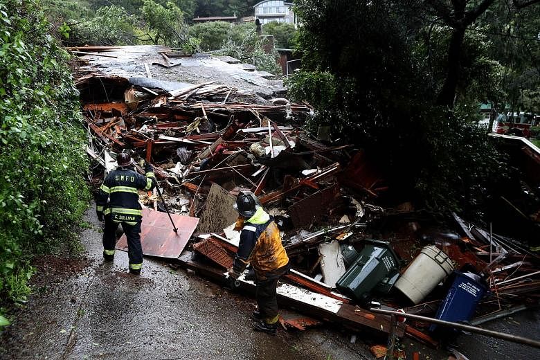 Southern Marin firefighters searching a home that was swept downhill by a mudslide during a rainstorm in Sausalito, California on Thursday. Fifty homes were evacuated after the mudslide struck homes and sent at least one sliding 70m down a hill. No i