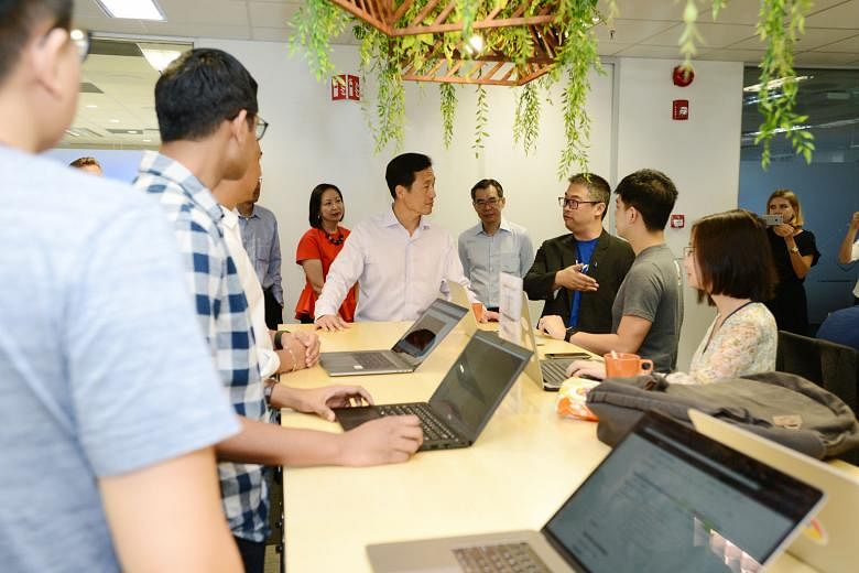 Education Minister Ong Ye Kung (centre) speaking to a PayPal employee at its international headquarters in Singapore. The American company is partnering with tertiary institutes in a programme where students will learn to apply PayPal's payment solut