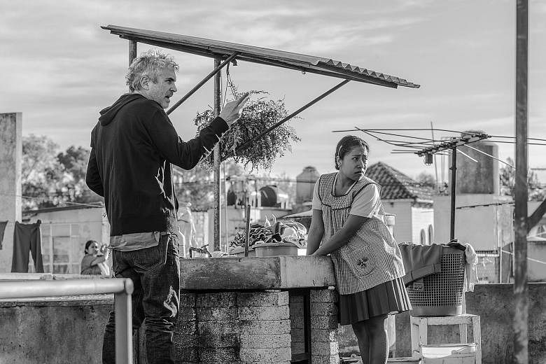 Roma, a Spanish-language movie set in 1970s Mexico City, has a documentary-like feel. It highlights the resilience of Cleo (Yalitza Aparicio, right), a housekeeper based on writer-director Alfonso Cuaron's (left) childhood nanny. 