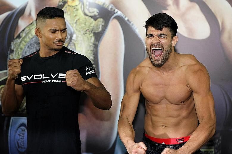 Singaporean mixed martial arts fighter Amir Khan looks hardly impressed as Ariel Sexton flexes his muscles at the open workouts at Evolve at Far East Square yesterday, ahead of One Championship's Call to Greatness event on Friday. Amir, 24, will face