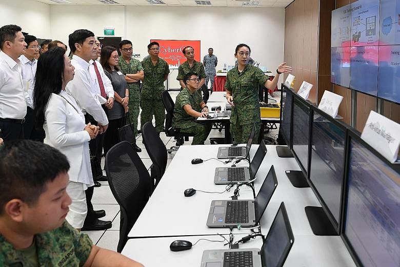 Senior Minister of State for Defence Heng Chee How (second from left) and members of the Advisory Council on Community Relations in Defence (Accord) watching a demonstration of cyber operators performing incident response in the Cyber Defence Test an