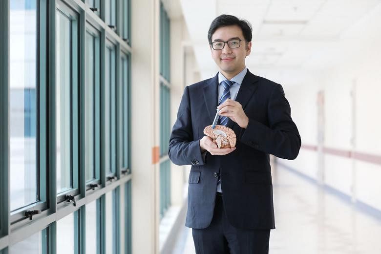 National Neuroscience Institute neurosurgery research director Nicolas Kon with a BrainPath obturator (blue) inside a sheath (transparent) and a model of the brain. It took him a year of trying before he succeeded in bringing the method to Singapore.