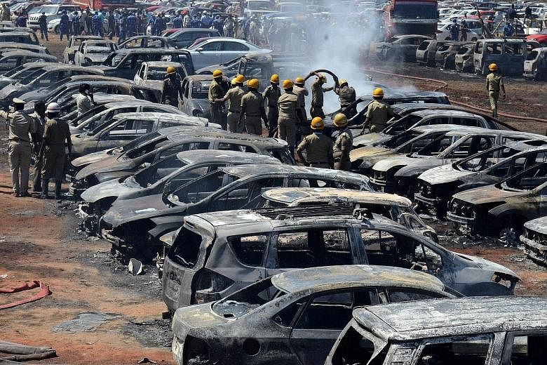 Firefighters extinguishing smouldering cars after a fire at the carpark on Saturday during Aero India 2019, one of the world's biggest air shows, at the Yelahanka air base in Bangalore, India. At least 300 vehicles were caught in the blaze, which spr