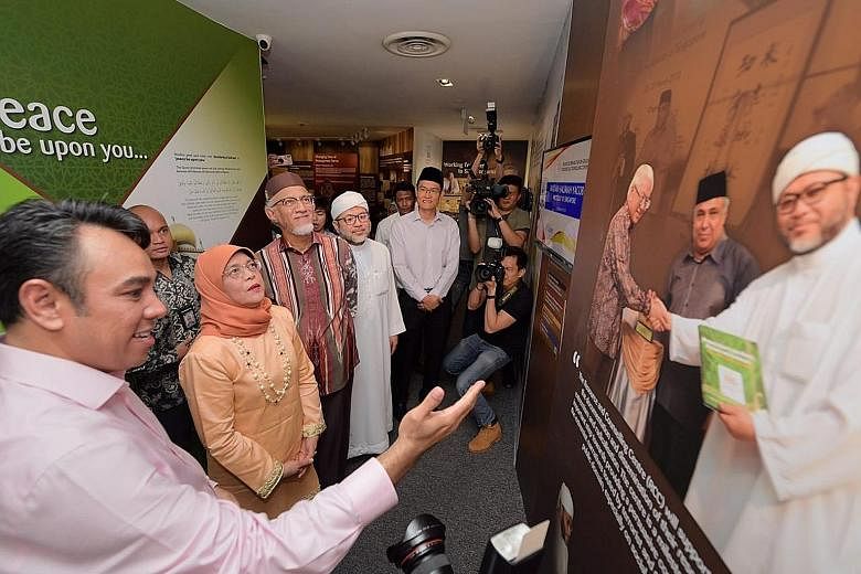 Religious Rehabilitation Group (RRG) vice-chairman Mohamed Ali (left) showing President Halimah Yacob and her husband, Mr Mohamed Abdullah Alhabshee, around the RRG resource and counselling centre at the Khadijah Mosque during their visit yesterday.