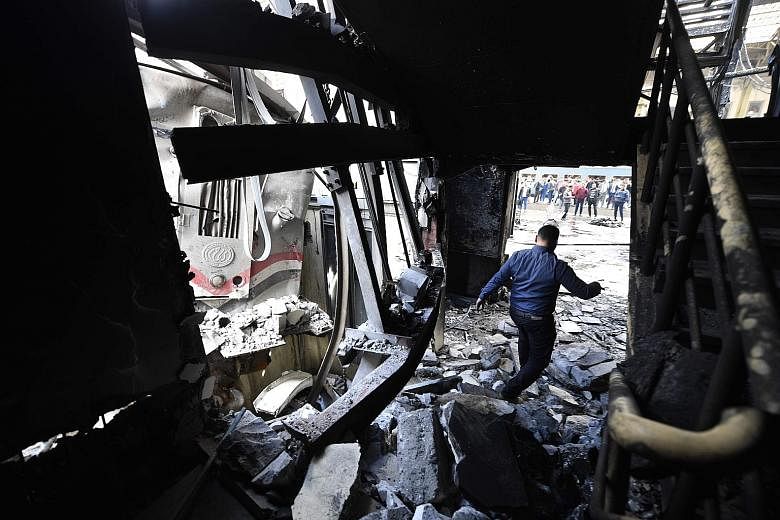 Left: People surveying the charred engine of the train which crashed through the buffers at the main train station in the Egyptian capital Cairo yesterday. Below: A man amid the debris at the scene of the accident.