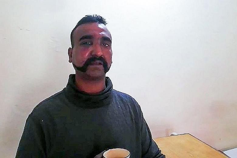 Pakistanis reading about the shooting down of an Indian fighter jet yesterday. Islamabad says the captured pilot, Indian Wing Commander Abhinandan Varthaman (above), will be released today.