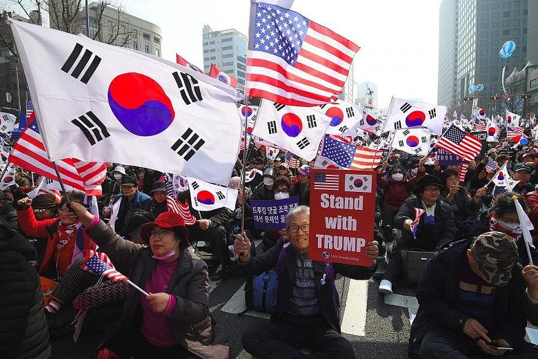 Pro-American protesters waving South Korean and US flags during a rally denouncing the South Korean government's dovish approach and policies on North Korea in Seoul yesterday.