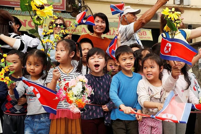 Above: Children cheering as North Korean leader Kim Jong Un's motorcade passed by in Hanoi yesterday. Left: Mr Kim, accompanied by Vietnamese President Nguyen Phu Trong, attending a welcome ceremony at the Presidential Palace in Hanoi yesterday. Mr K