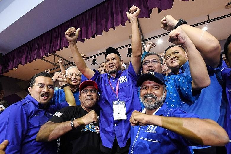 Above: BN's winning candidate, Mr Zakaria Hanafi (centre, shirt with BN logo), celebrating with former premier Najib Razak (second from left) and other party supporters yesterday. Left: PH's Mr Muhammad Aiman Zainali, who lost, casting his vote yeste