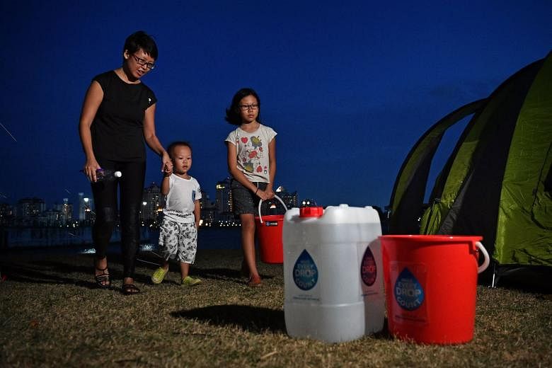 Ms Adeline Goh, her son Ging Wai, four, and daughter Yan Wan, 10, outside their tent at the water conservation camp.