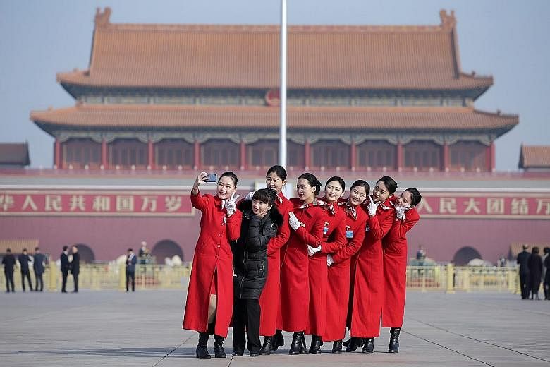 Attendants taking a group selfie at Tiananmen Square yesterday ahead of the National People's Congress opening today. Premier Li Keqiang is expected to announce measures to boost domestic demand.