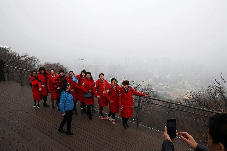 Chinese tourists posing for a photo with the view of central Seoul shrouded by fine dust in the background yesterday.