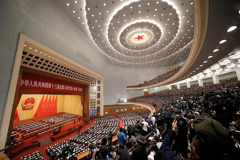 Delegates and journalists attending the National People's Congress held at the Great Hall of the People in Beijing yesterday. People taking photos while waiting for the flag-raising ceremony at Tiananmen Square before the NPC's opening yesterday.