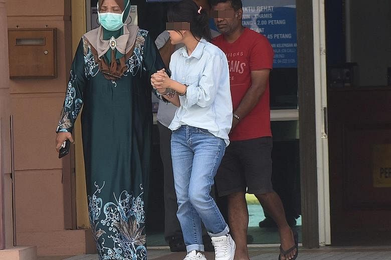 Two handcuffed suspects in the murder of an IT manager being led out of the Penang Hospital mortuary on Tuesday. The police are also hunting a "fair-skinned foreign man". The three people were seen entering a condominium with the victim - Mr Brian Pa