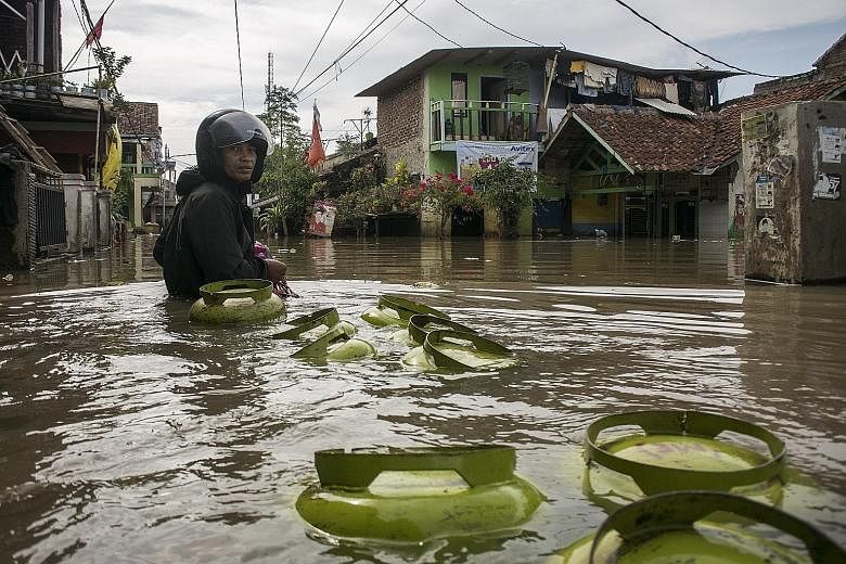 A deliveryman hauling cylinders of liquefied petroleum gas had to wade through murky floodwaters in Bojong Asih, in the Indonesian city of Bandung, as he went on his rounds yesterday. Residents on the outskirts of Bandung have been forced to walk in 